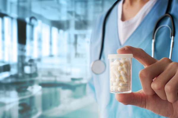 Doctor holding pill container in lab setting