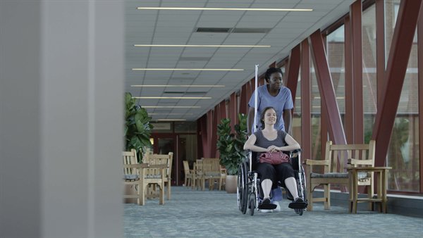 Nurse assisting woman in wheelchair indoors