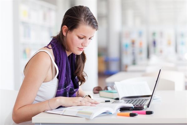 Young woman studying with laptop and books