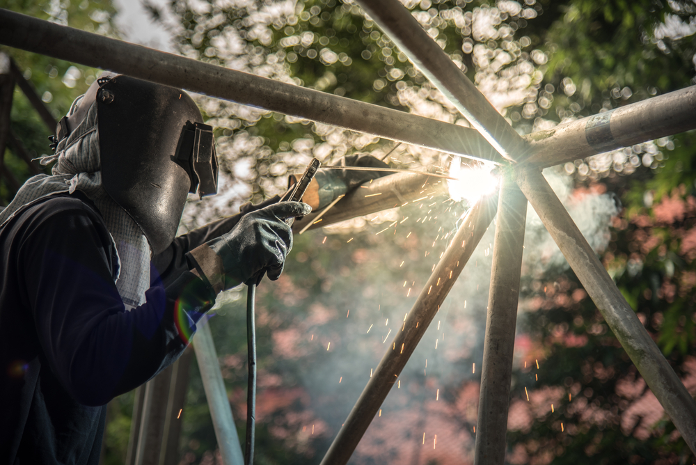 Welder working on metal structure outdoors